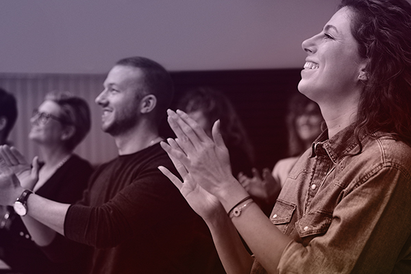 Tyytyväiset yleisön edustajat taputtavat katsomossa käsiään