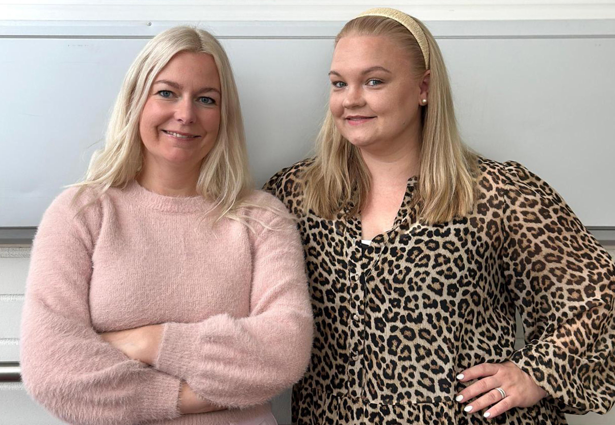 Kaksi vaaleaa naista hymyilee kameraan kuvattuina vyötäröstä ylöspäin